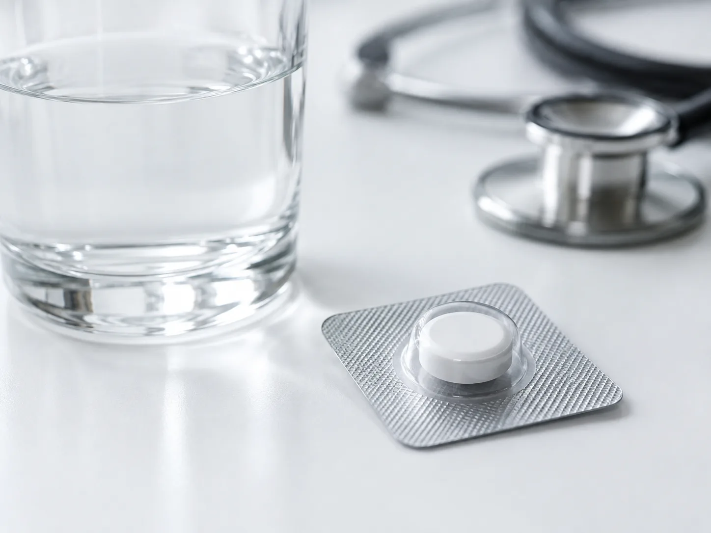 A modafinil tablet in its blister pack beside a glass of water and a stethoscope